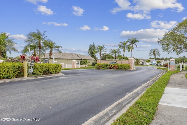 view of street featuring a residential view, a gated entry, curbs, a gate, and sidewalks