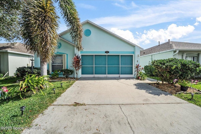 view of front facade with a garage, driveway, and stucco siding