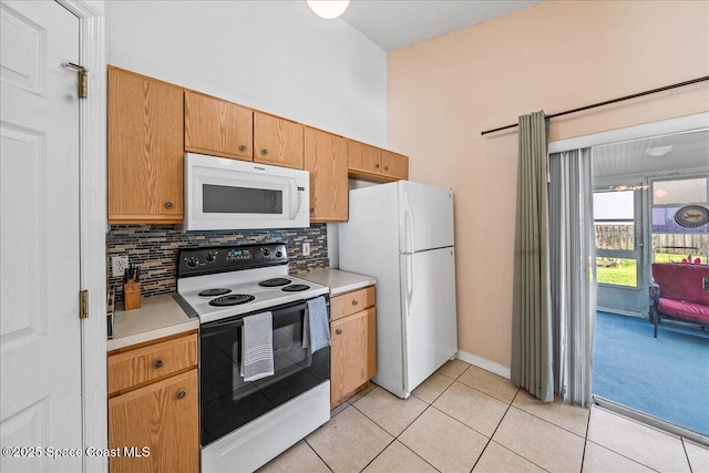 kitchen with light tile patterned floors, light countertops, white appliances, and backsplash