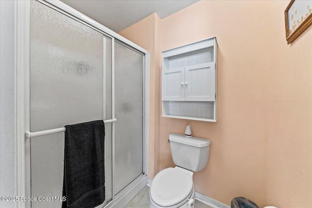 full bath with toilet, a stall shower, and baseboards