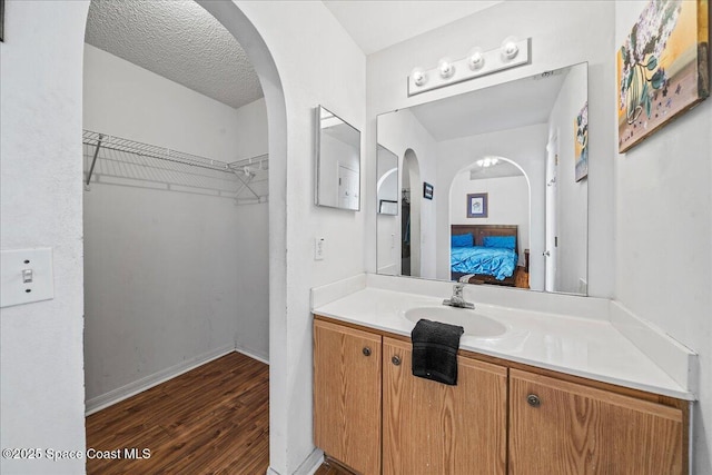 ensuite bathroom with baseboards, wood finished floors, ensuite bathroom, a textured ceiling, and vanity