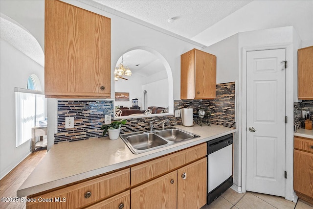 kitchen with dishwasher, lofted ceiling, light countertops, a textured ceiling, and a sink