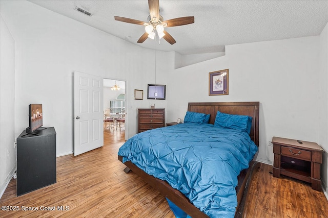 bedroom with lofted ceiling, a textured ceiling, and wood finished floors