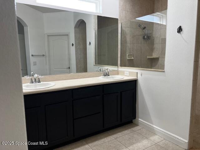 bathroom with tile patterned flooring, vanity, and a tile shower