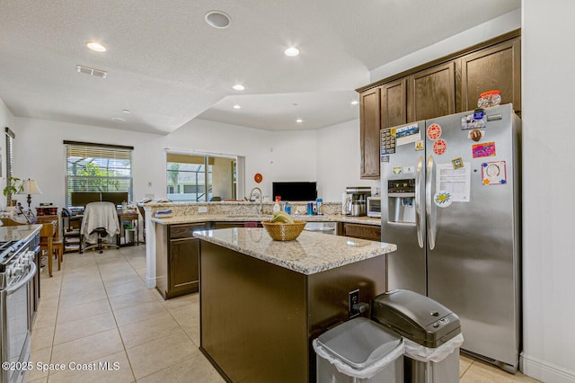 kitchen with a kitchen island, kitchen peninsula, range with gas cooktop, and stainless steel fridge with ice dispenser