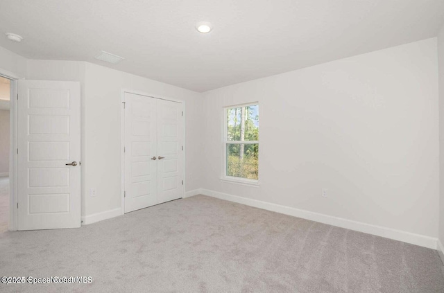 unfurnished bedroom featuring light colored carpet and a closet