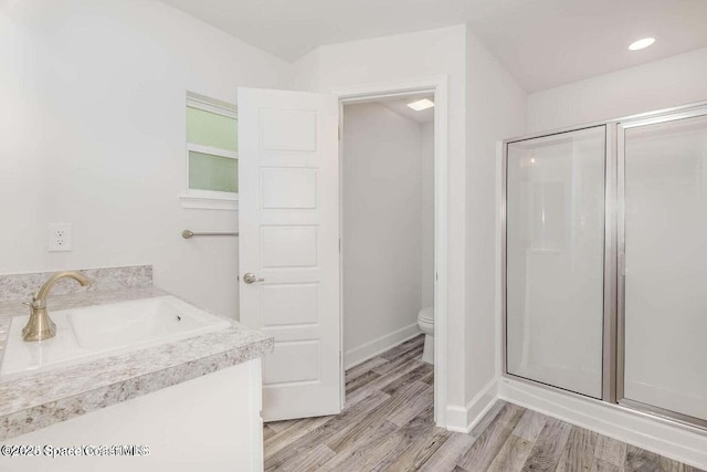 full bathroom with toilet, vanity, a shower stall, wood finished floors, and baseboards