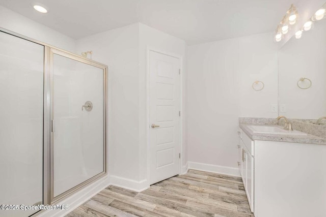 bathroom with wood-type flooring, vanity, and a shower with shower door