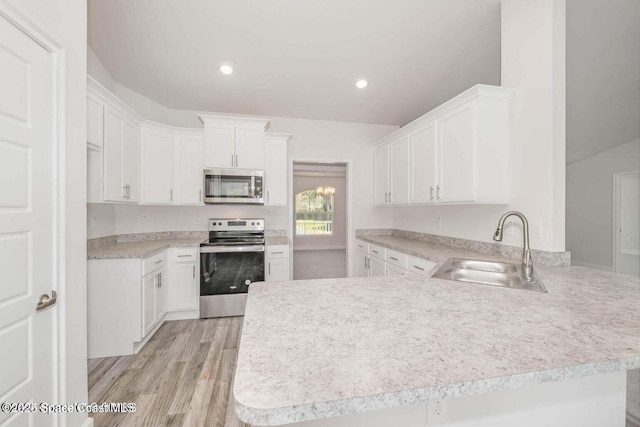 kitchen featuring white cabinetry, sink, kitchen peninsula, stainless steel appliances, and light hardwood / wood-style flooring