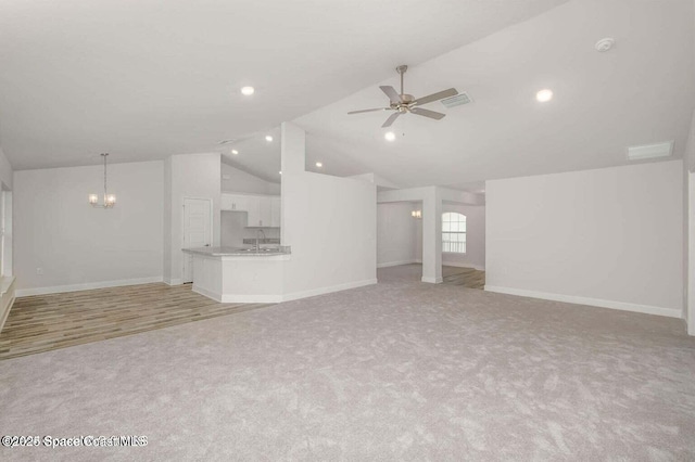 unfurnished living room with lofted ceiling, ceiling fan with notable chandelier, light colored carpet, and baseboards