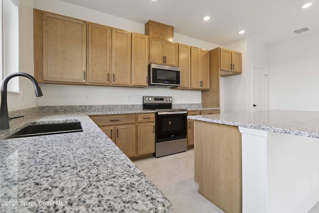 416 Glaspell Cir SE, Palm Bay, FL 32909 - kitchen featuring appliances with stainless steel finishes, recessed lighting, light stone countertops, light tile patterned floors, and brown cabinets