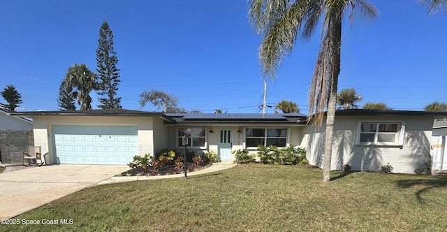 single story home featuring a garage, a front yard, and solar panels