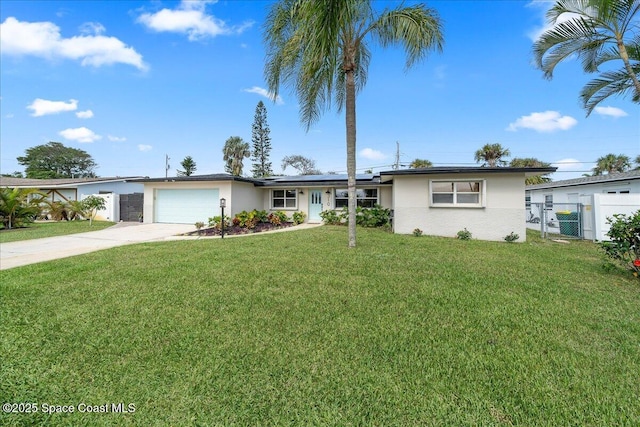 single story home with a garage, solar panels, a front lawn, and concrete driveway