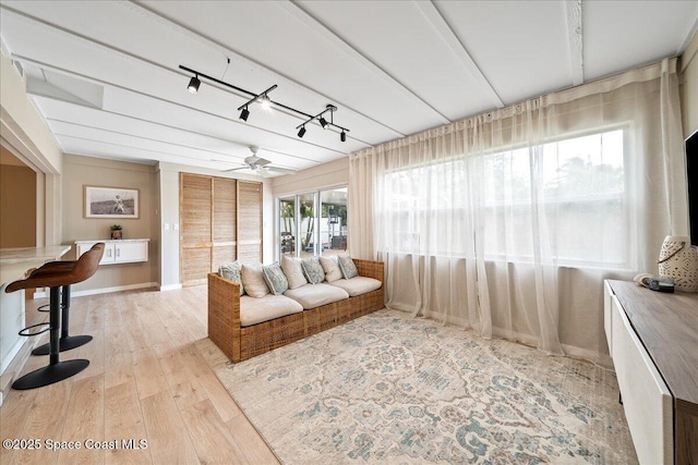 living room featuring rail lighting, ceiling fan, baseboards, and wood finished floors