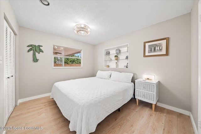 bedroom with a textured ceiling, a closet, light wood-style flooring, and baseboards