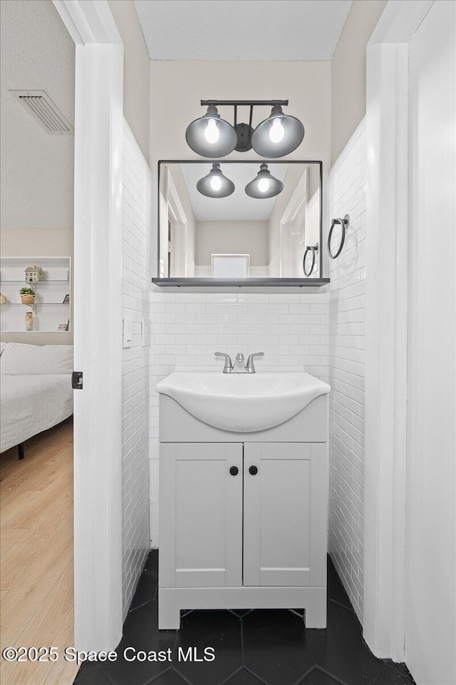 bathroom featuring visible vents, ensuite bathroom, tile walls, and vanity