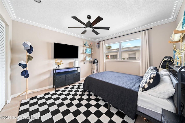 bedroom with ceiling fan, crown molding, baseboards, and a textured ceiling