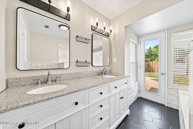 bathroom featuring double vanity, visible vents, a sink, and tile patterned floors