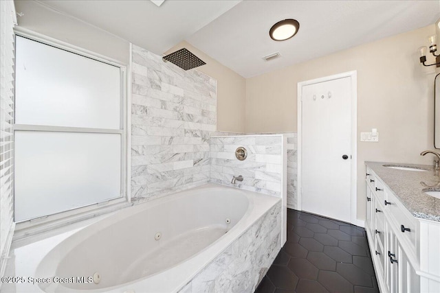 bathroom featuring double vanity, visible vents, a tub with jets, tile patterned floors, and a sink