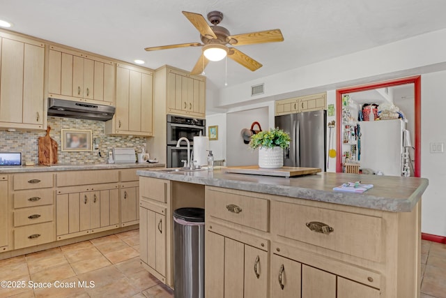 kitchen featuring light brown cabinetry, tasteful backsplash, a kitchen island with sink, light tile patterned floors, and stainless steel appliances