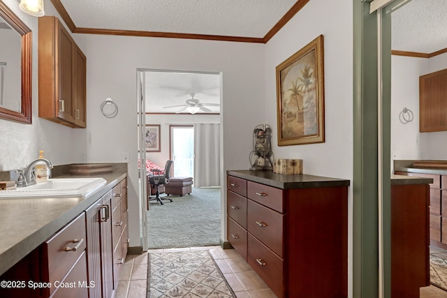 kitchen featuring sink, crown molding, light carpet, a textured ceiling, and ceiling fan