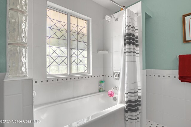 bathroom featuring shower / bath combo with shower curtain and tile walls