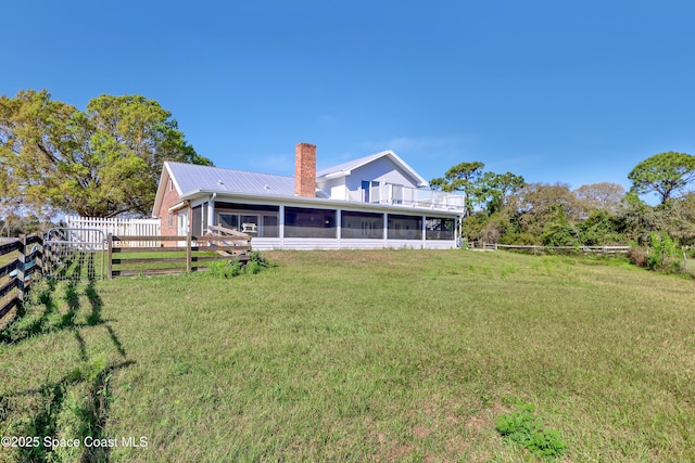 back of house featuring a sunroom and a lawn