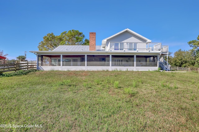 back of house featuring a sunroom and a lawn