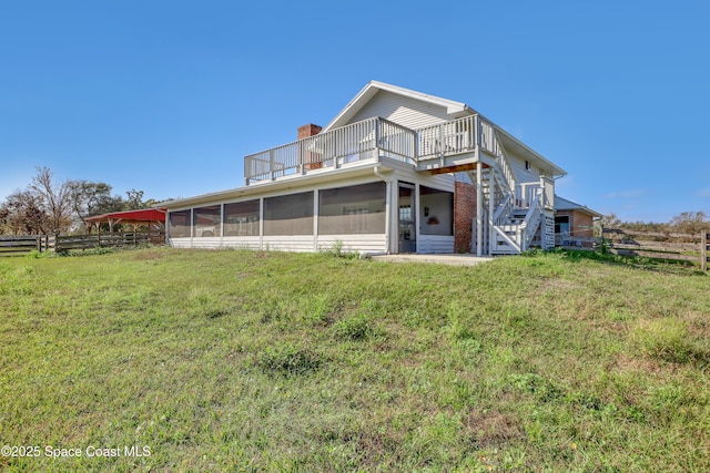 rear view of property featuring a yard and a sunroom