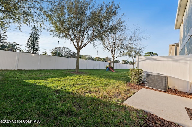 view of yard with a fenced backyard and central AC