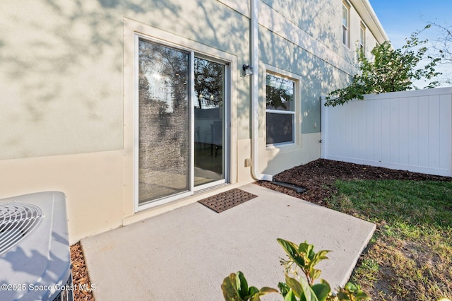 exterior space with a patio area, fence, and stucco siding