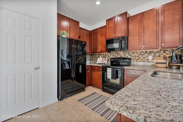 kitchen with light tile patterned floors, light stone counters, a sink, black appliances, and backsplash