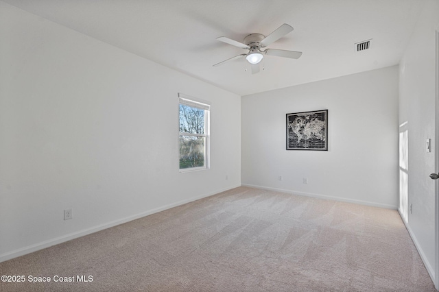 spare room with light carpet, ceiling fan, visible vents, and baseboards