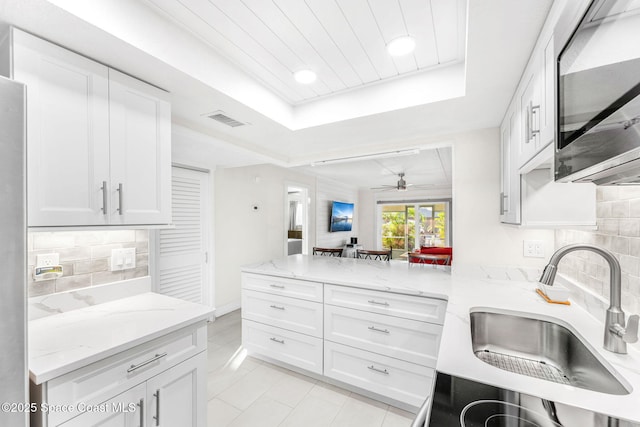 kitchen featuring white cabinetry, sink, and a tray ceiling