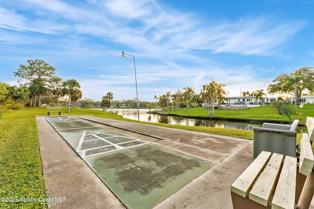 surrounding community with a water view and a lawn