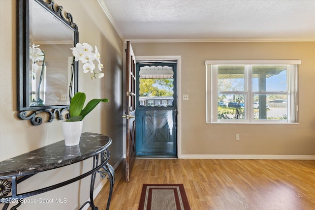 entryway featuring a healthy amount of sunlight, light wood-type flooring, crown molding, and a textured ceiling