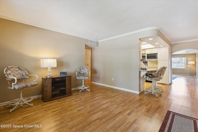 interior space with ornamental molding, visible vents, light wood-style flooring, and baseboards