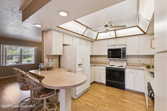 kitchen featuring white cabinetry, electric range, white refrigerator with ice dispenser, and stainless steel microwave