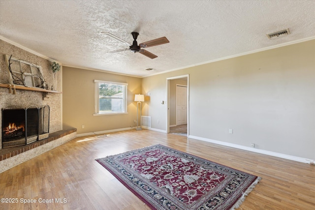 living room featuring a large fireplace, wood finished floors, visible vents, and crown molding