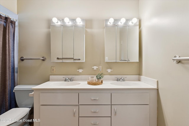 bathroom with toilet, double vanity, and a sink