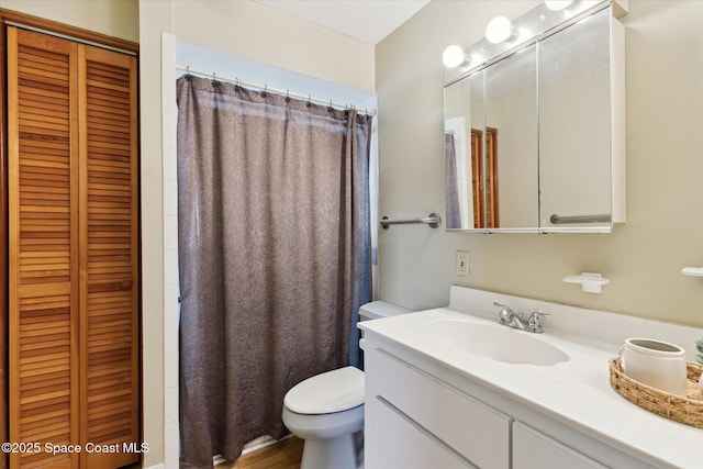 bathroom featuring toilet, a closet, and vanity