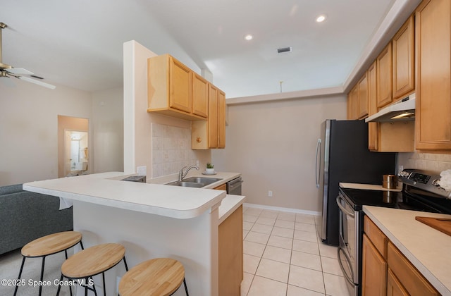 kitchen featuring sink, light tile patterned floors, a breakfast bar, appliances with stainless steel finishes, and tasteful backsplash