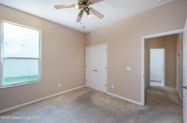 unfurnished bedroom featuring ceiling fan, light colored carpet, and a closet