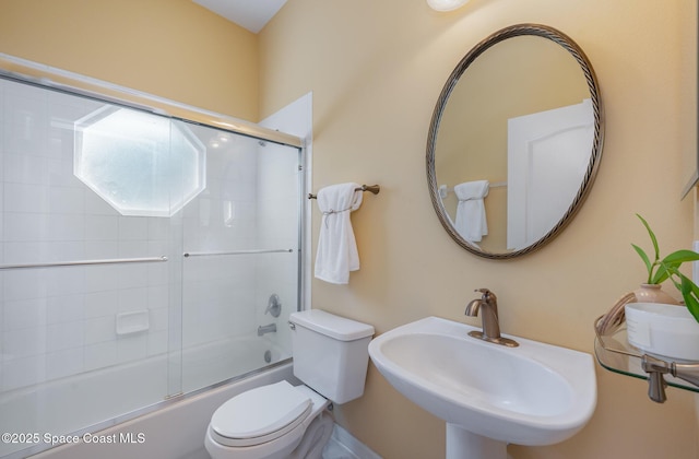 full bathroom featuring bath / shower combo with glass door, toilet, and sink