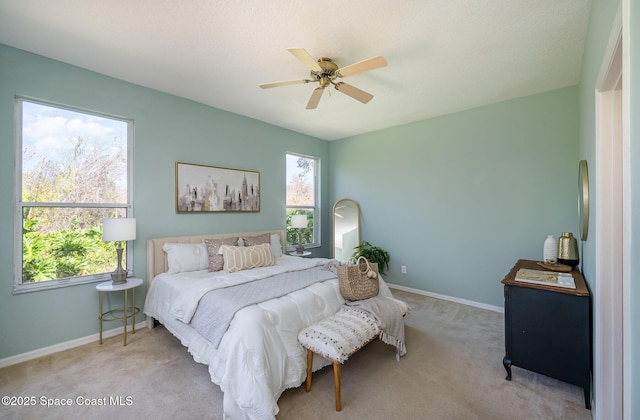 bedroom featuring multiple windows, light colored carpet, and ceiling fan