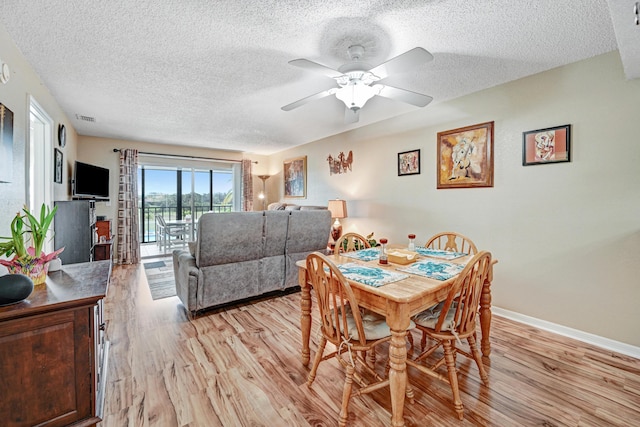 dining room with ceiling fan, a textured ceiling, and light hardwood / wood-style floors