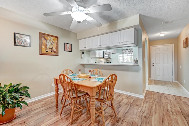 dining area featuring ceiling fan, a textured ceiling, and light hardwood / wood-style floors