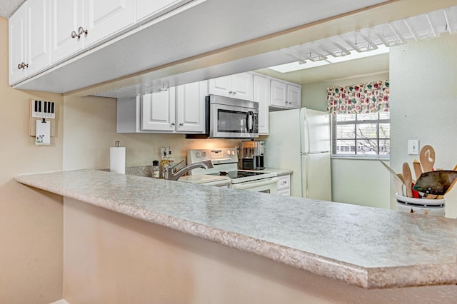 kitchen with white cabinetry, white appliances, and kitchen peninsula