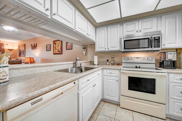 kitchen featuring white cabinetry, sink, light tile patterned flooring, and white appliances