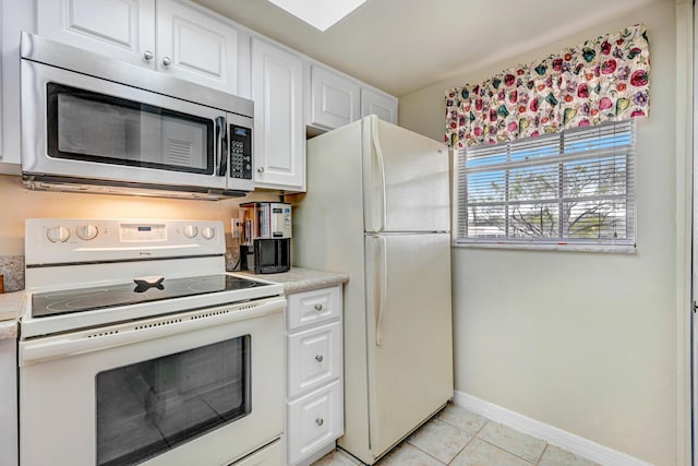 kitchen featuring white appliances, light tile patterned floors, and white cabinets